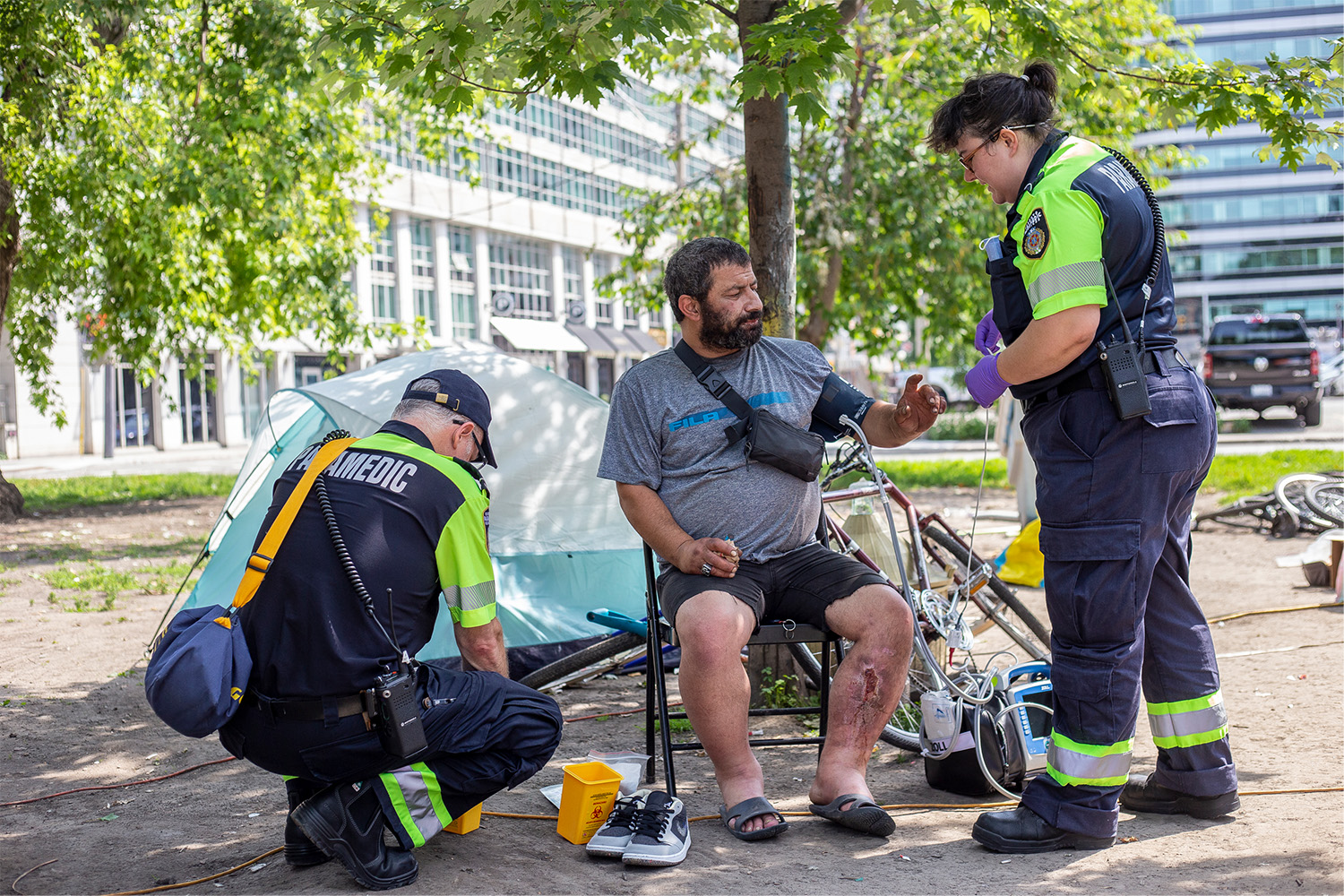 Toronto paramedics tend to Davit Sesisheili at Clarence Square Park, checking his vital signs and caring for his injured leg. 