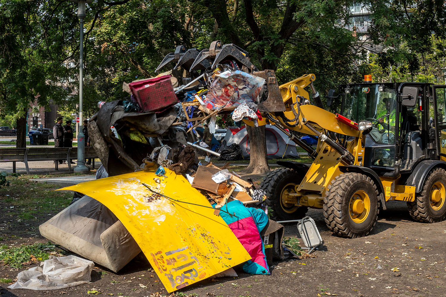 Following a fire the night before, city workers clear the remnants of a tent in Clarence Square Park on October 5, 2024. 