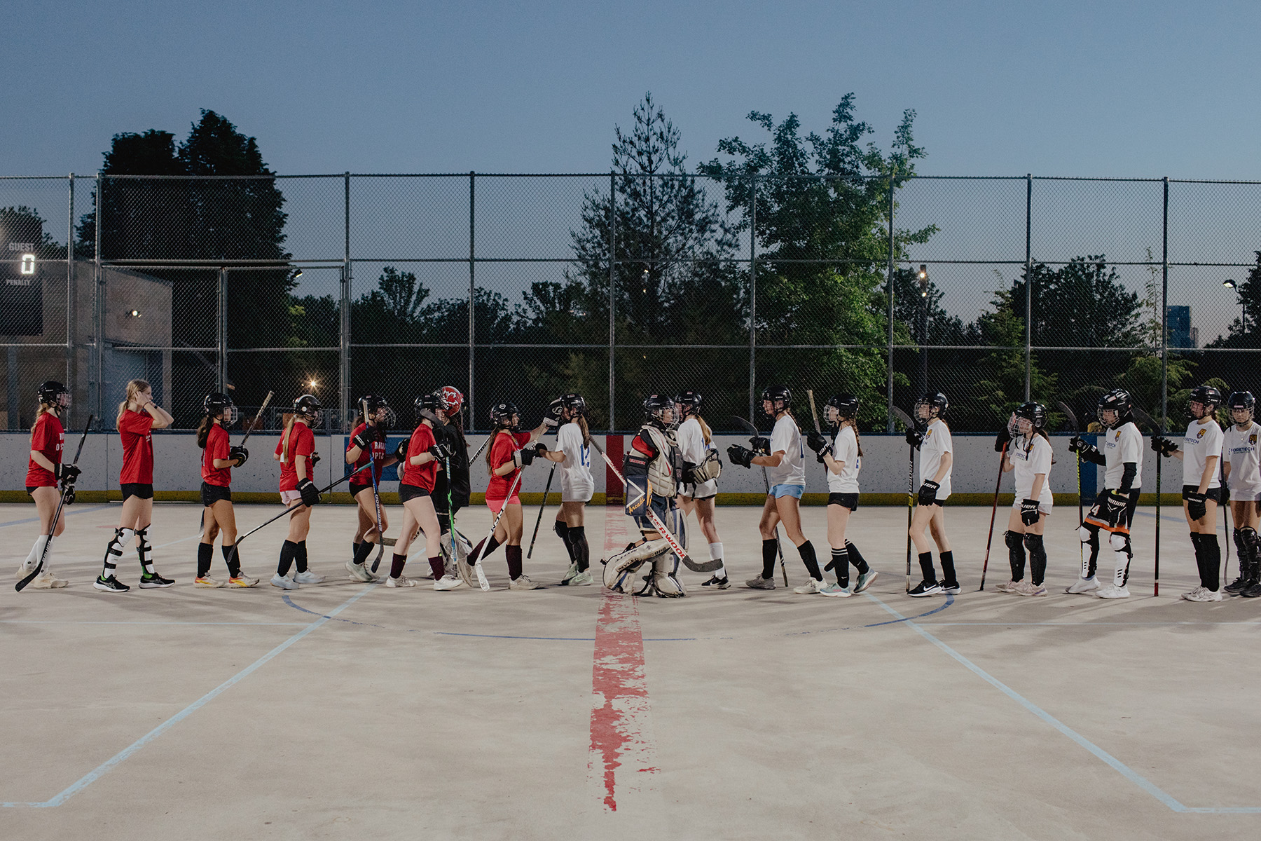 Ball hockey players shake hands at the end of a game in June.
