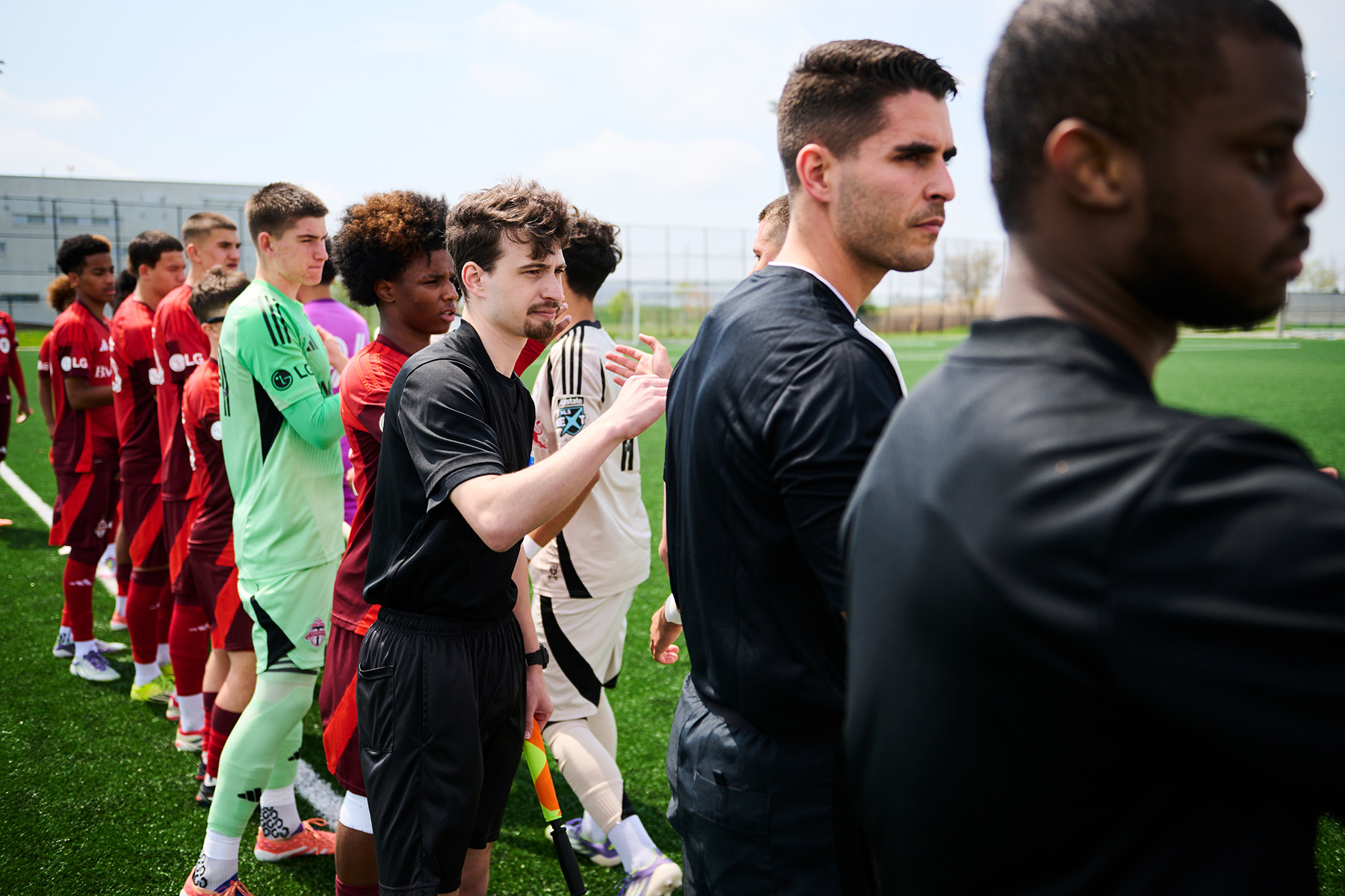 Referees Ben Kivenko, left, Josue Tomas and Jared Marshall shake hands with both teams before a game at Downsview Park.