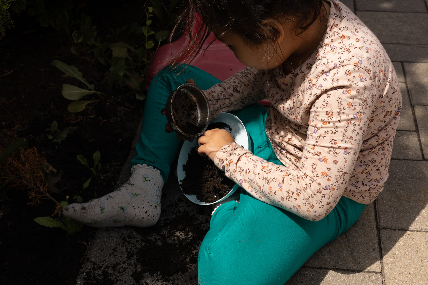 Katalina makes mud pies from the garden soil in her backyard. 