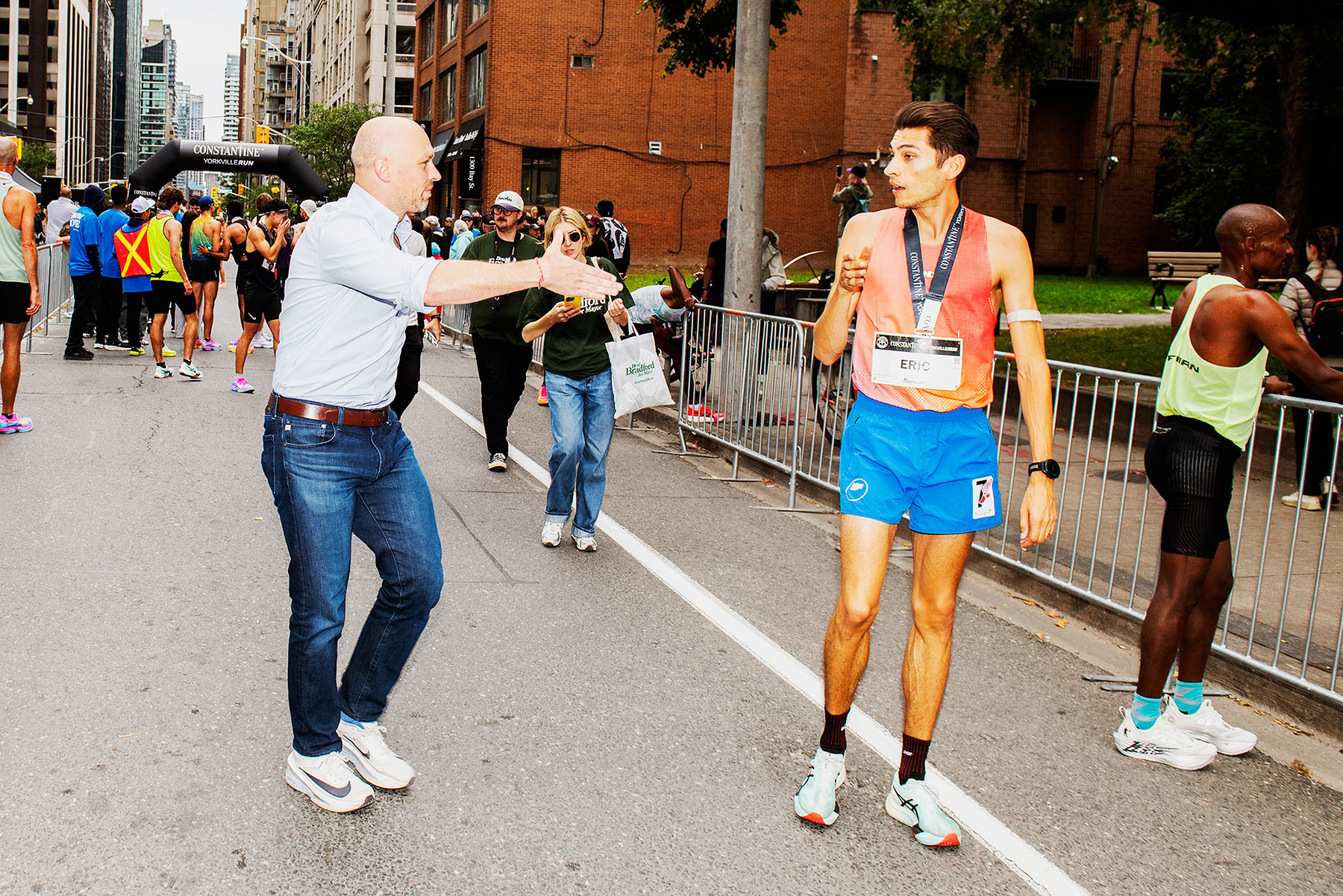 Bradford startles a runner while offering congratulations at the finish line of a charity run in Yorkville.